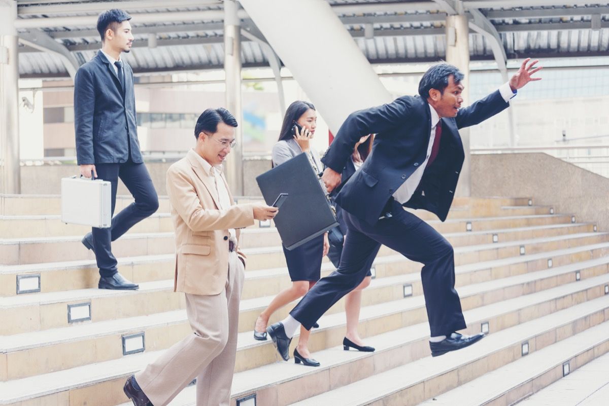 Omul de afaceri asiatic trece pe trepte, trecând pe lângă alți trei oameni de afaceri, etichetă peste 40