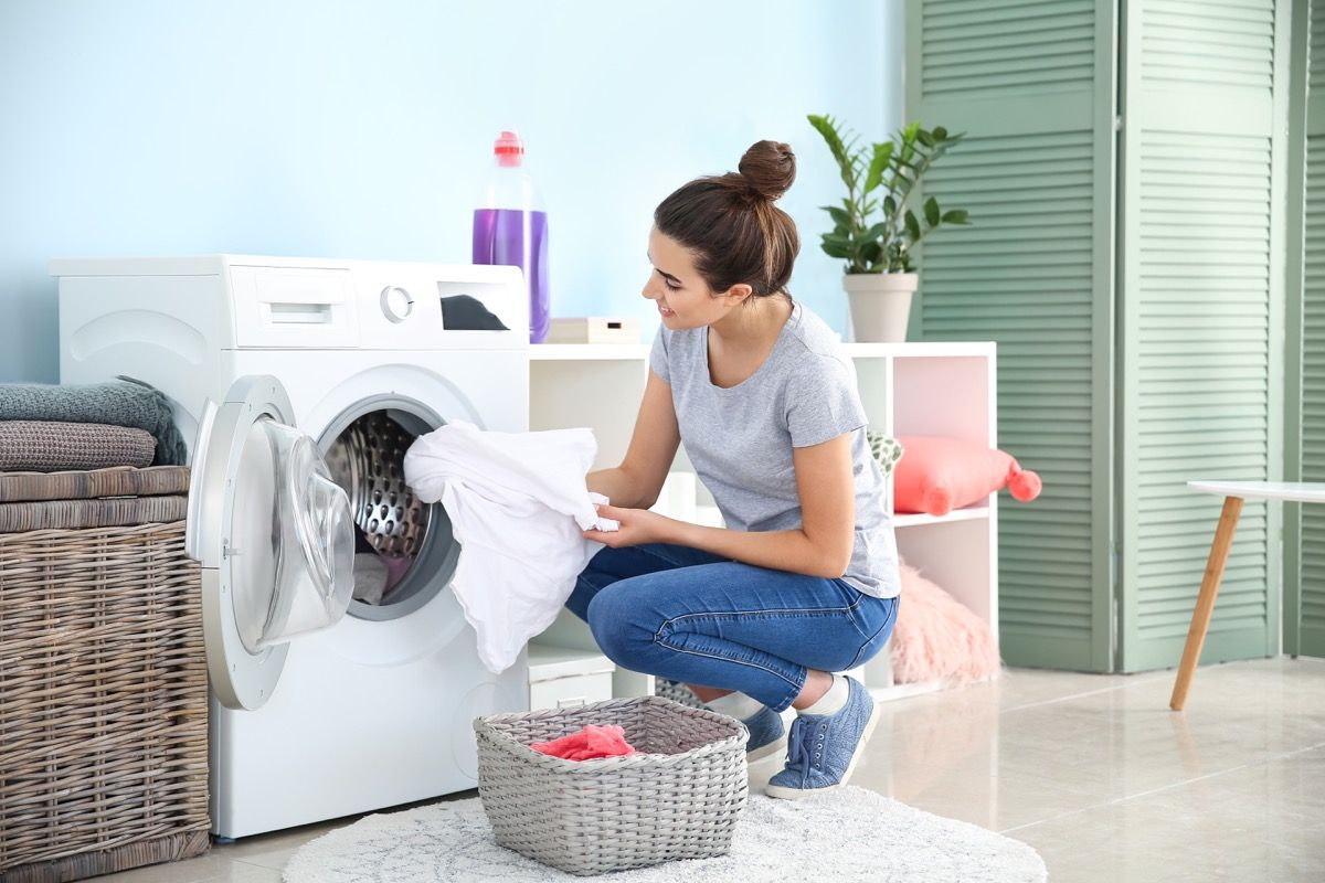 Жена слага спално бельо в пералнята на пералнята