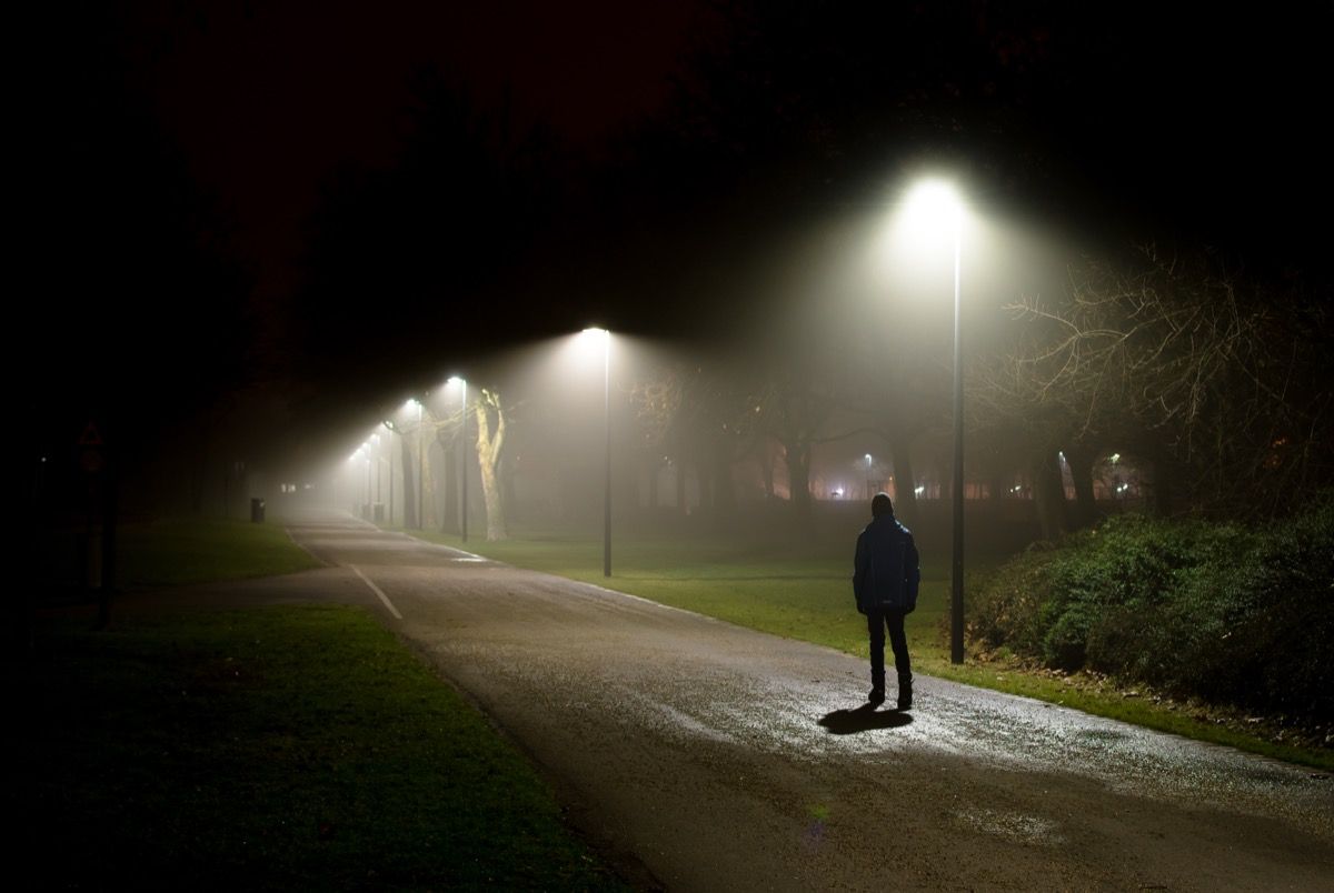 naktimis tamsioje gatvėje einantis vienas žmogus