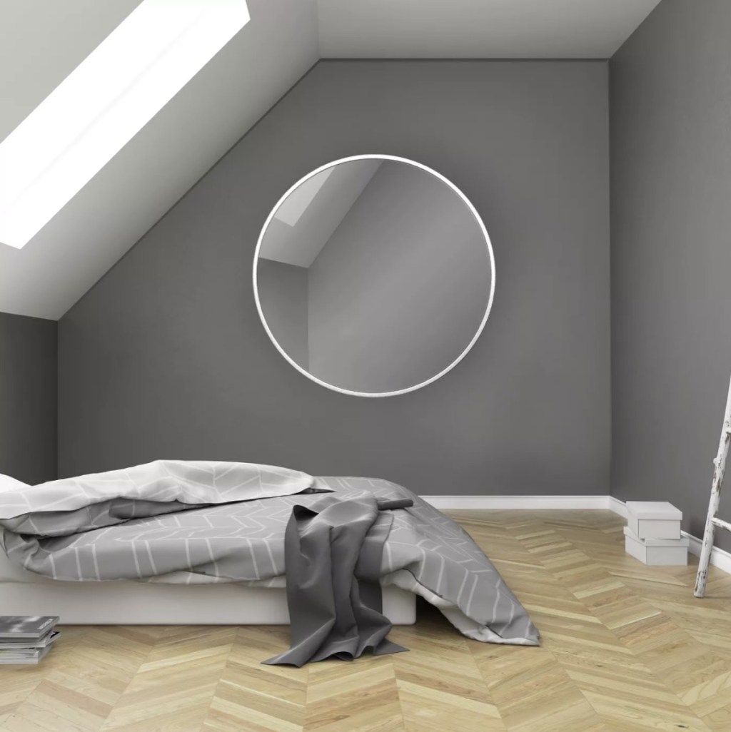 сива стая с легло на пода и кръгло огледало, предмети за домашен декор