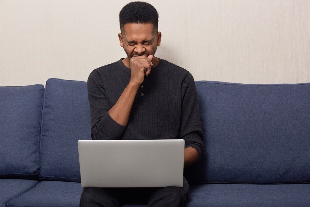 Hombre bosteza mientras se desplaza en su computadora portátil Síntomas de ataque cardíaco silencioso Hombres