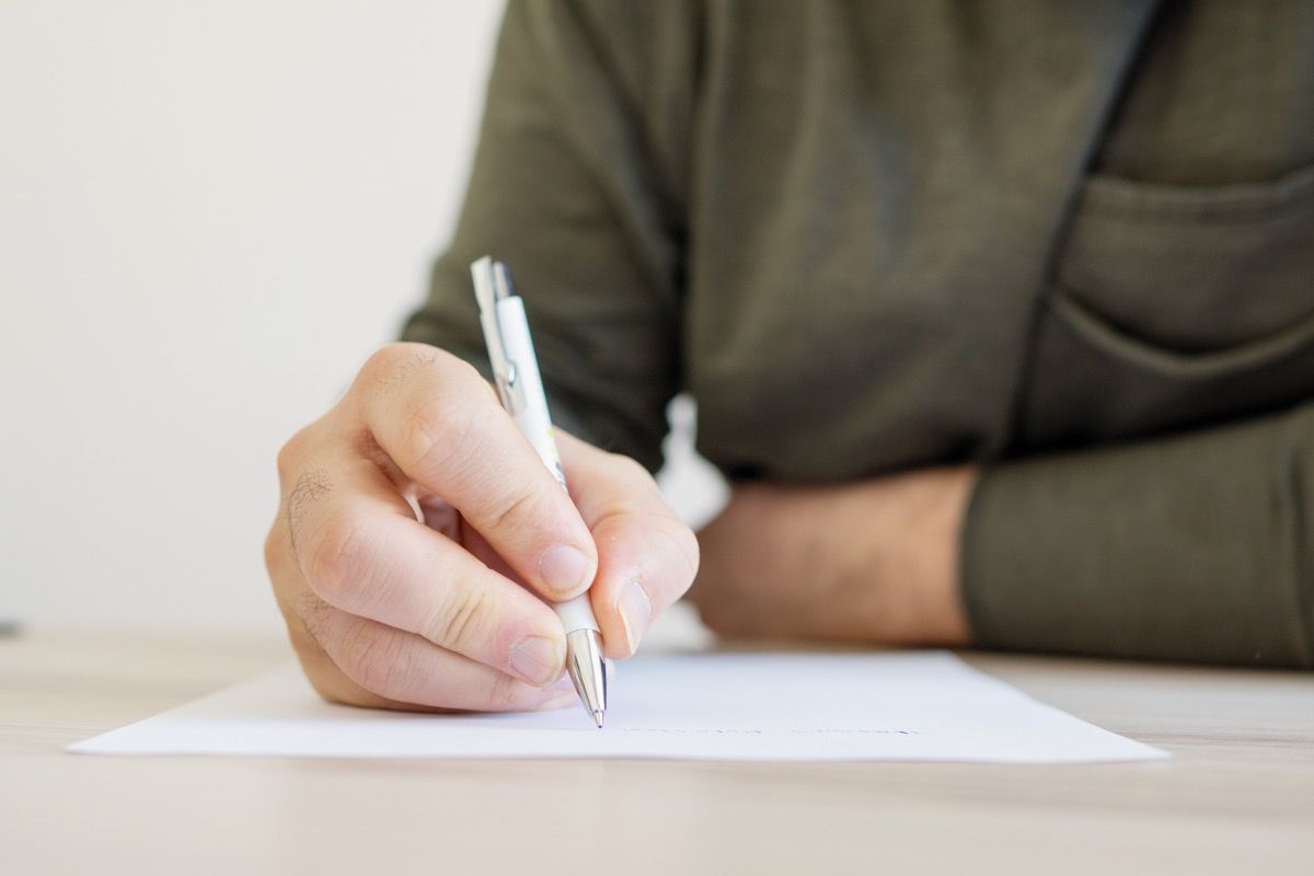 hombre escribiendo una carta con un bolígrafo
