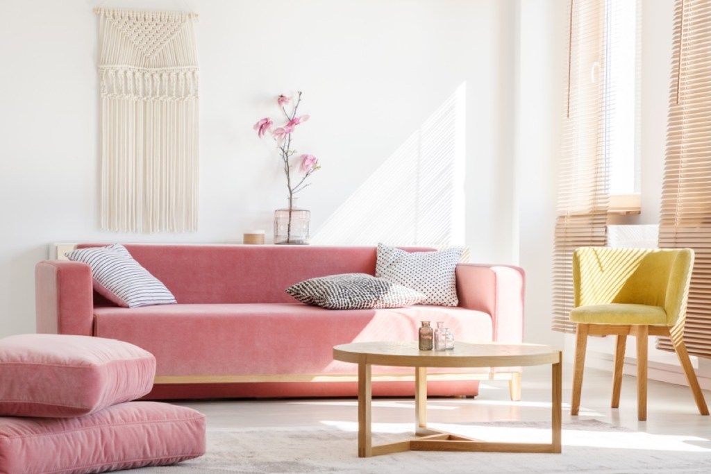 viesistaba ar rozā dīvānu un pufu