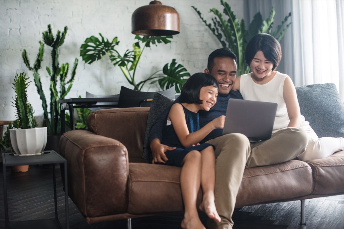 Perhe katselee kannettavaa tietokonetta sohvalla yhdessä