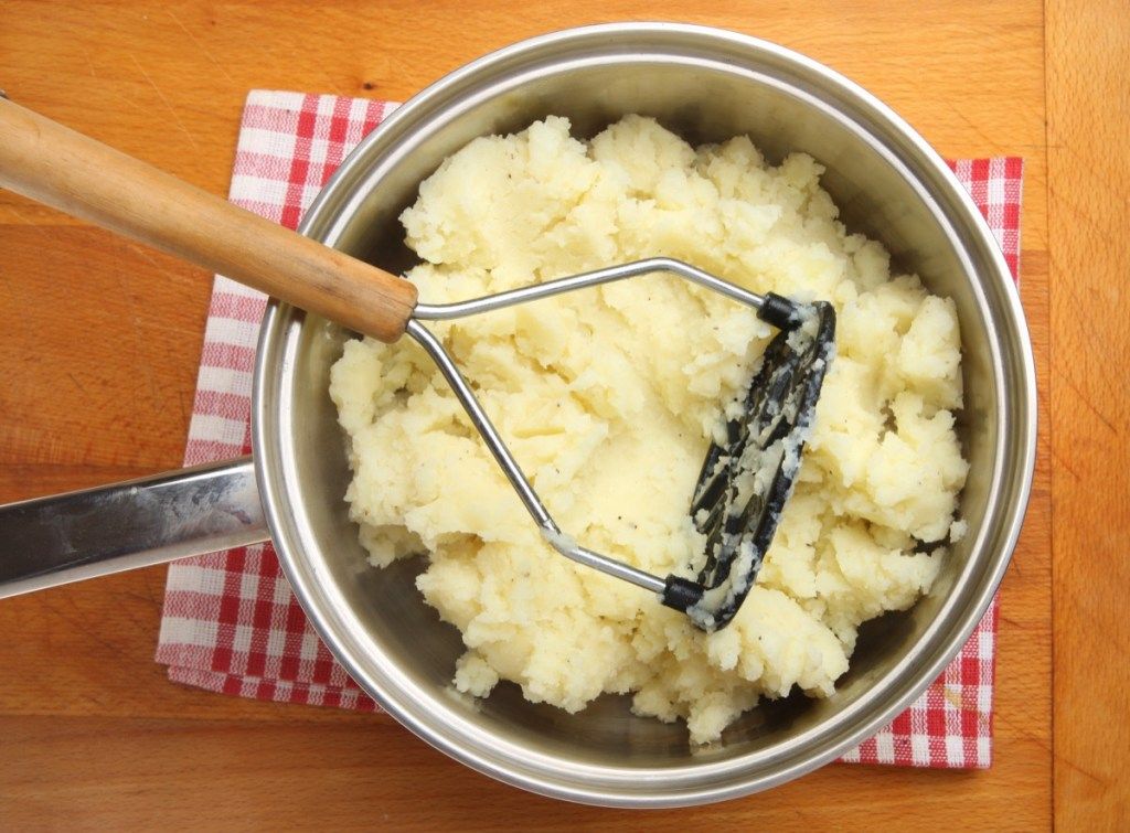 zilveren pot met aardappelpuree en aardappelstamper