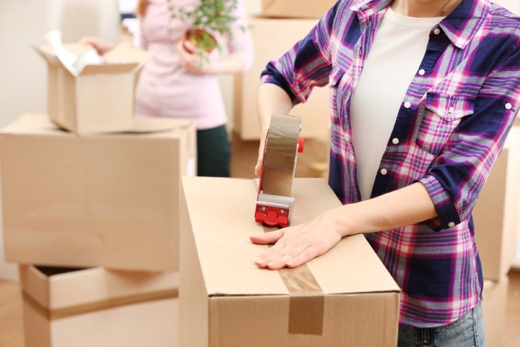 sievietes uzlīmē kustīgas kastes, samazinot jūsu māju skaitu