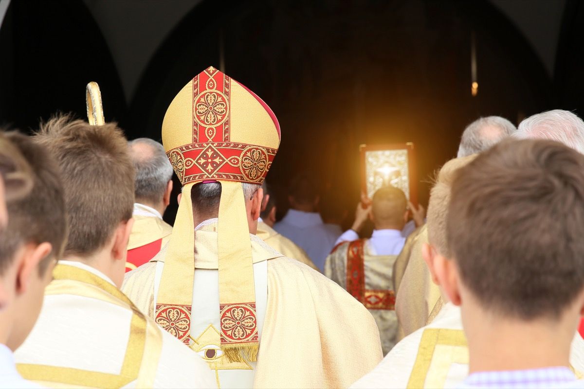 Škof gre skozi cerkev, ki ji sledijo oltarji