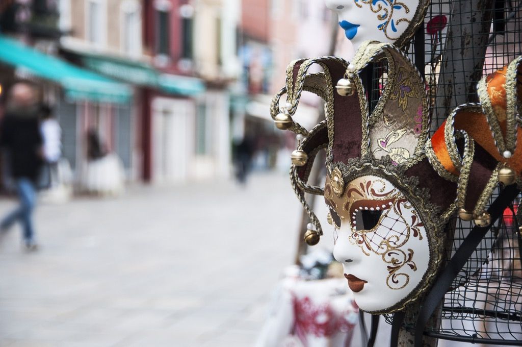 Venetiansk maske hengende utenfor en butikk i en italiensk gate