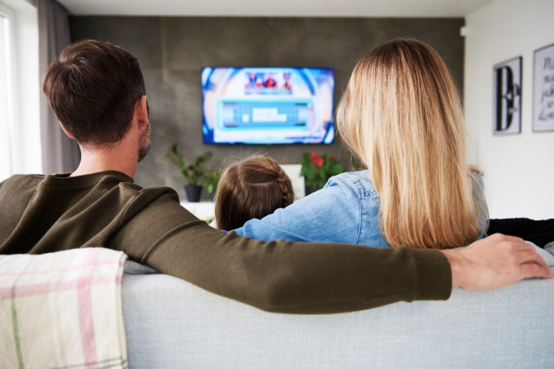   Семейство, седнало на дивана, докато гледа стрийминг телевизионна услуга