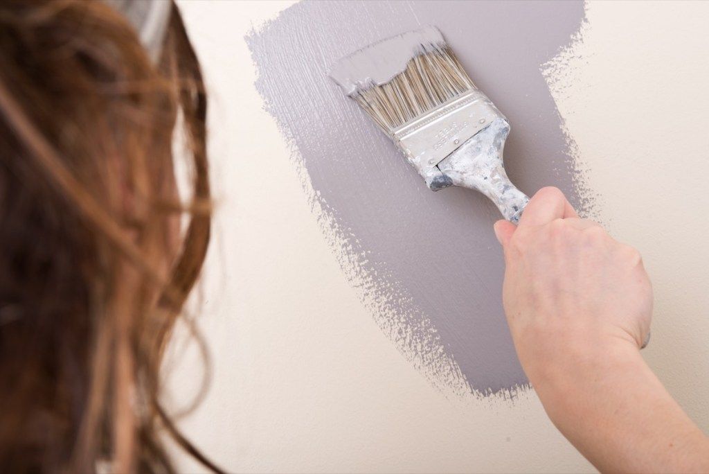 Mulher pintando as paredes de cinza