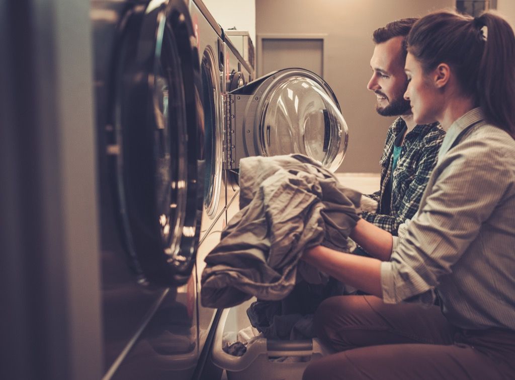 एक लॉन्ड्रोमैट में कपड़े धोने वाले युवा जोड़े
