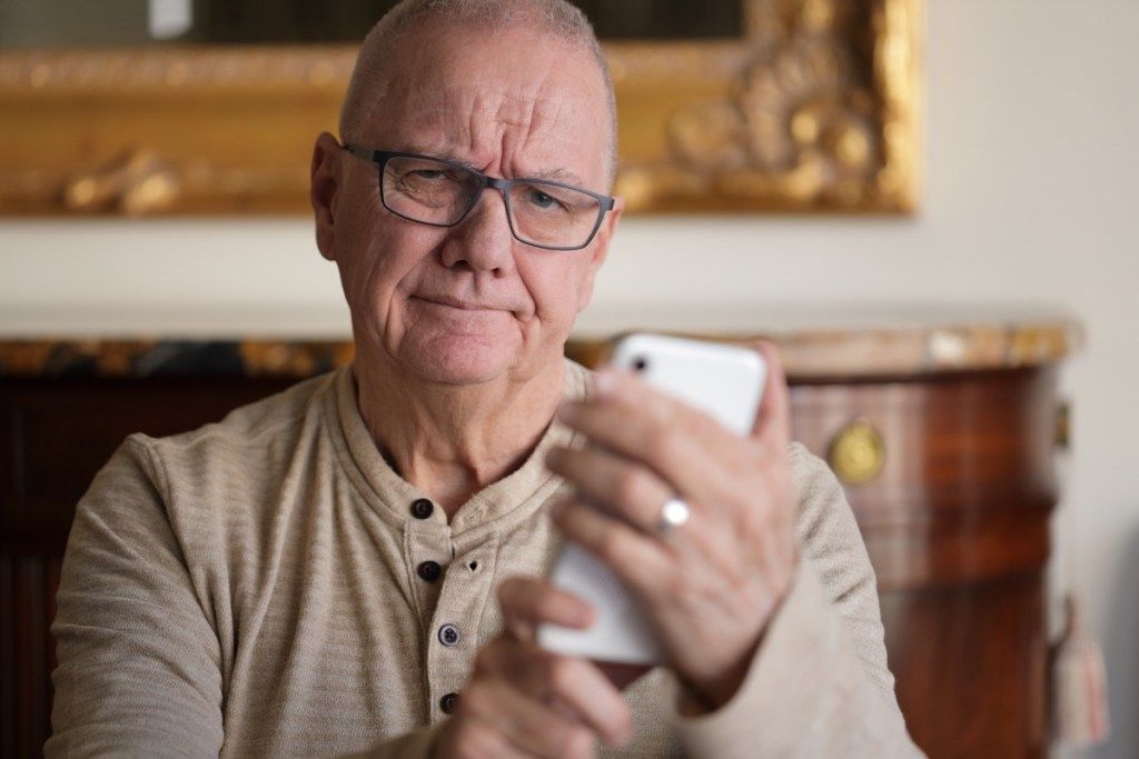 äldre man som har problem med sin telefon.