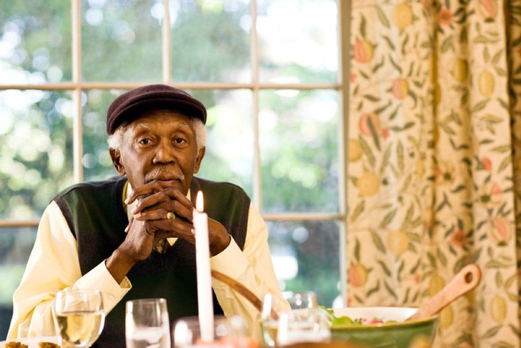 starejši moški s komolci na jedilni mizi, napake v bontonu
