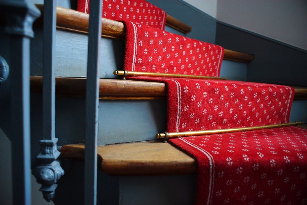 Zelta kāpņu stieņi uz kāpnēm ar sarkanu paklāju