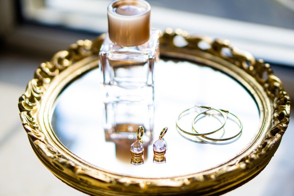 naušnice i bočica parfema na zlatnoj ladici s ogledalom