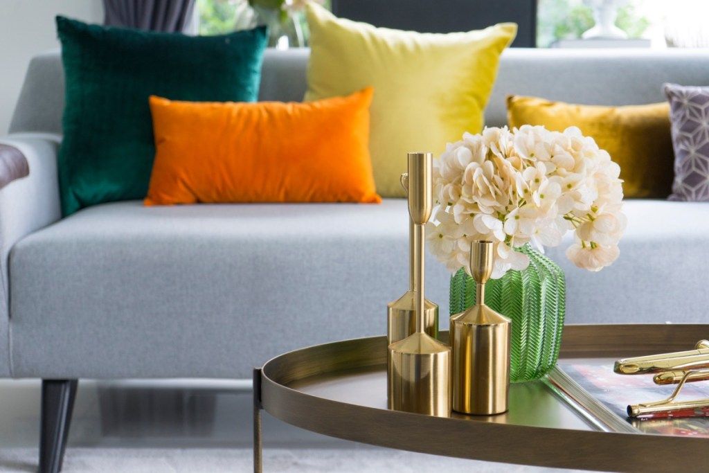 gullvaser og blomster på bord foran sofaen