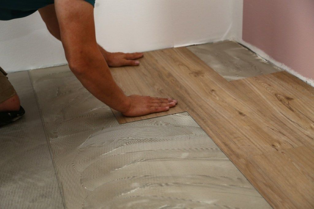 muž inštalujúci podlahu z drevených dlaždíc