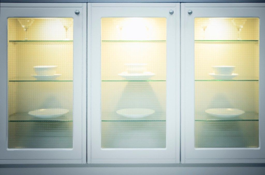 стаклени предњи кухињски ормар са белим посуђем изнутра