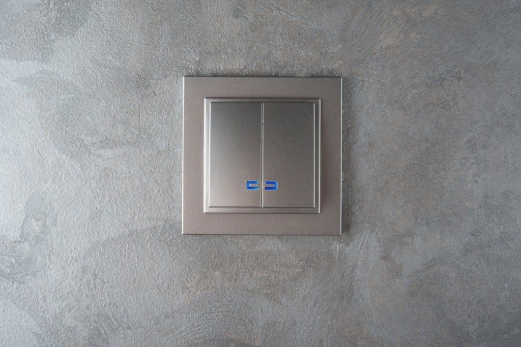 Placa de interruptor de luz plateada en pared gris