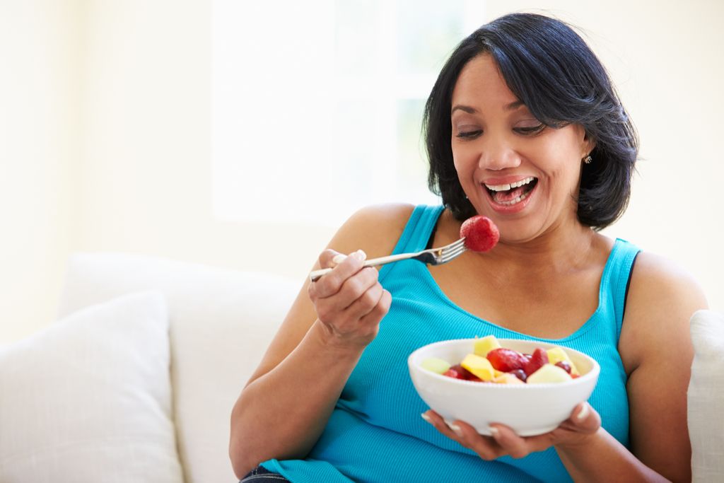 Mujer mayor comiendo fruta, se ve mejor después de los 40