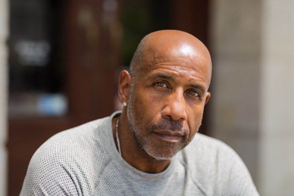 oudere zwarte man met lichte stoppels buitenshuis, ziet er beter uit na 40