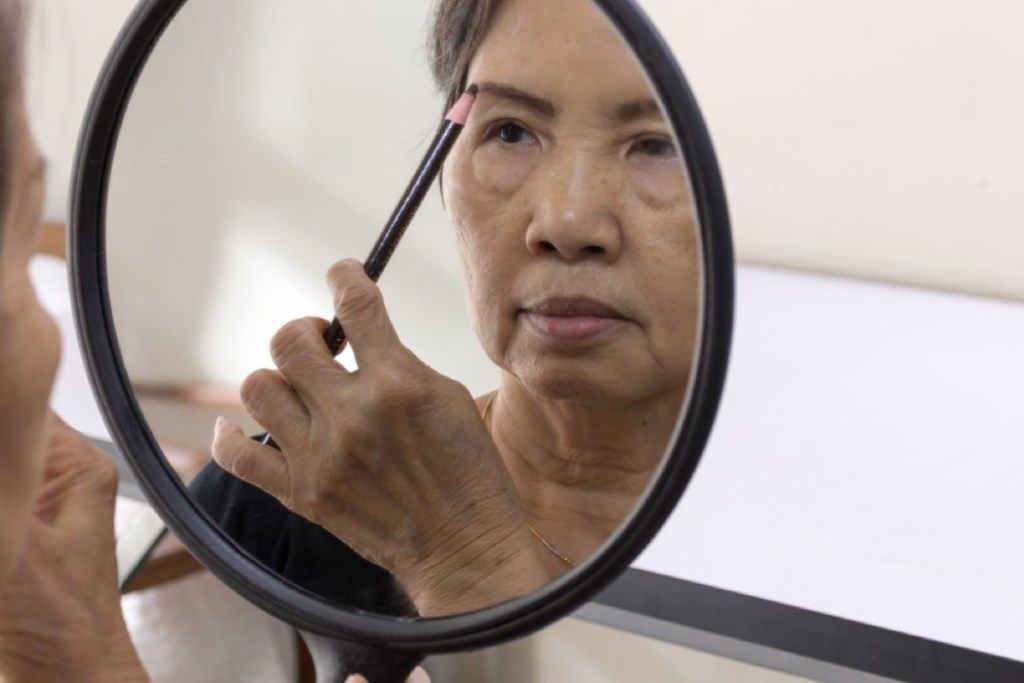 femeie mai în vârstă care aplică creionul pentru sprâncene, arată mai bine după 40 de ani