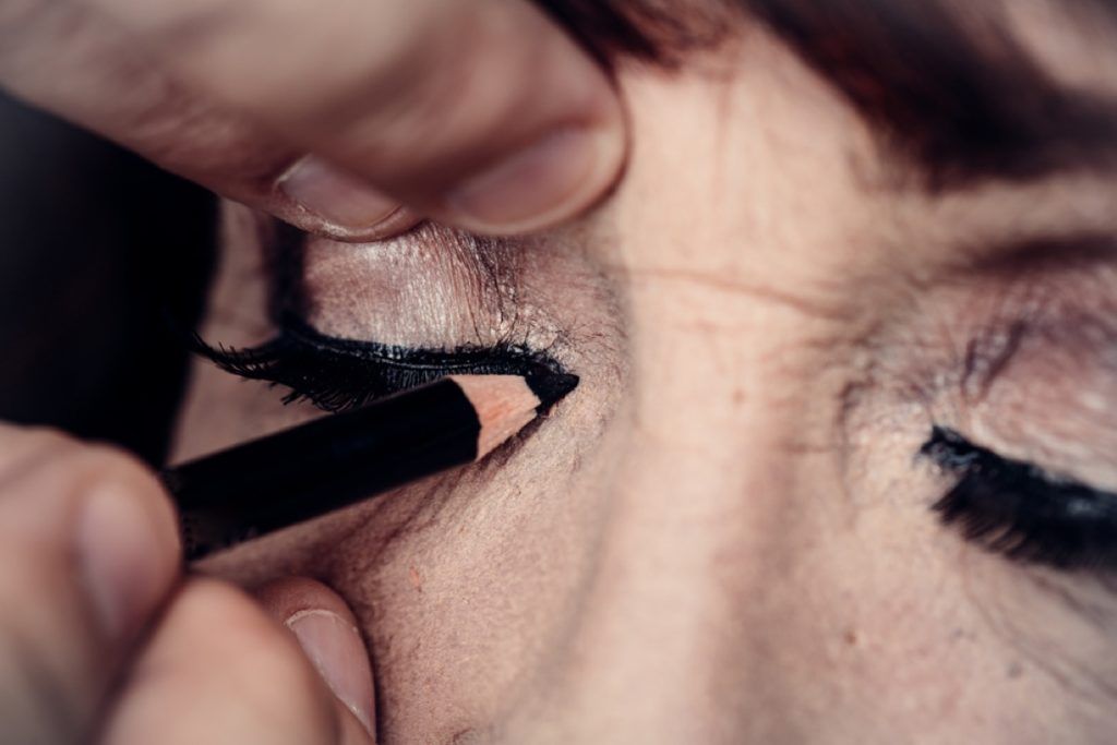 mujer mayor aplicando maquillaje de ojos, se ve mejor después de los 40