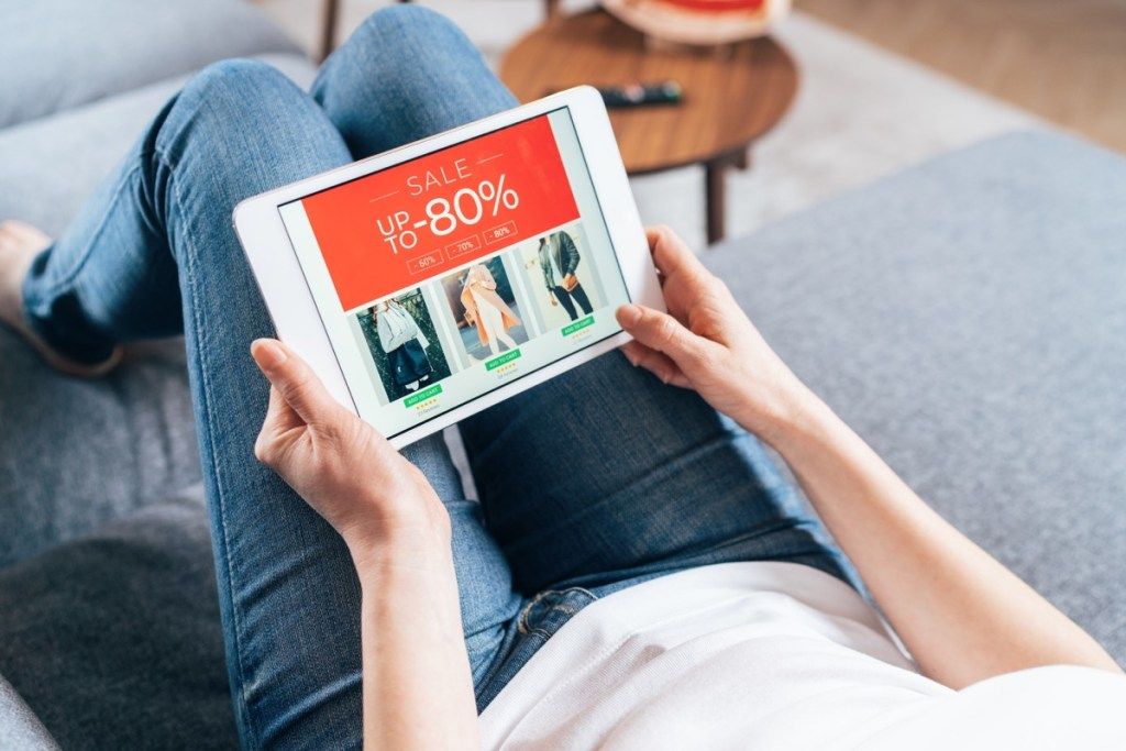 Femeie cumpărând vânzări online în sufrageria ei