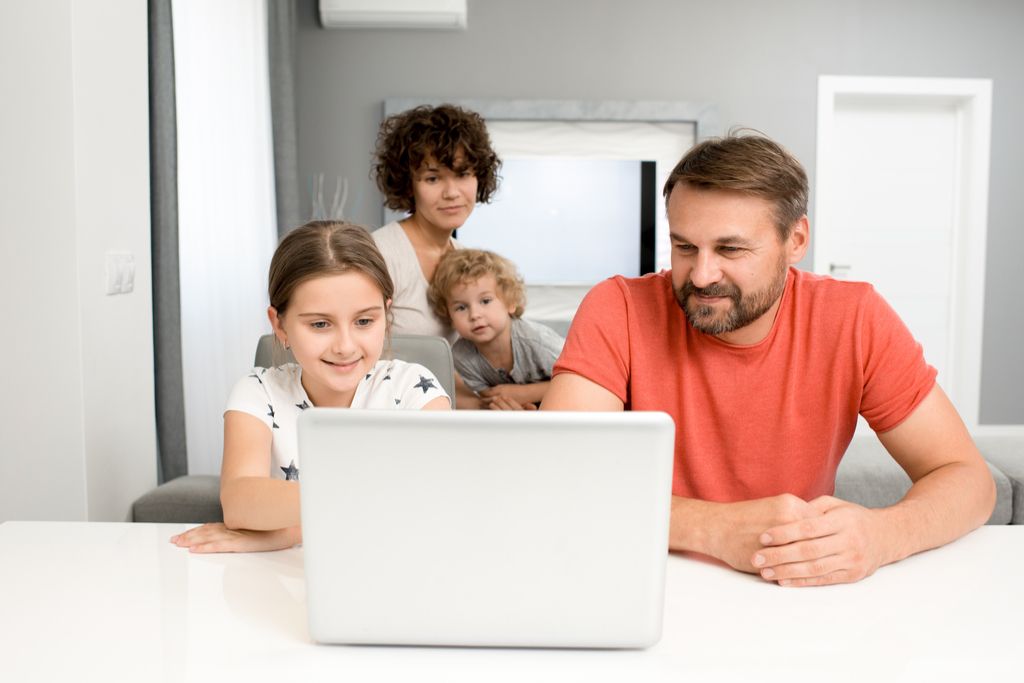 גבר, אישה, ושני ילדים קטנים מסתכלים על מחשב נייד