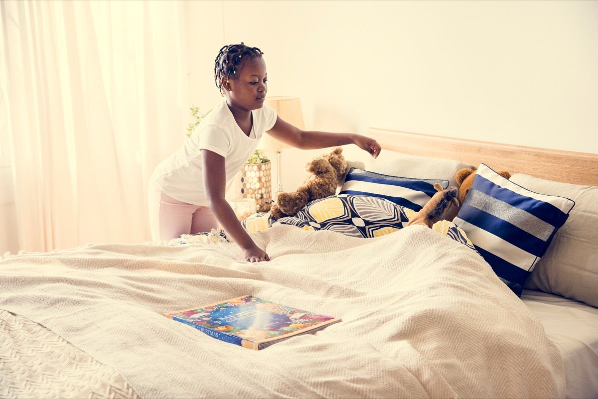 ילדה צעירה מסדרת את מיטתה
