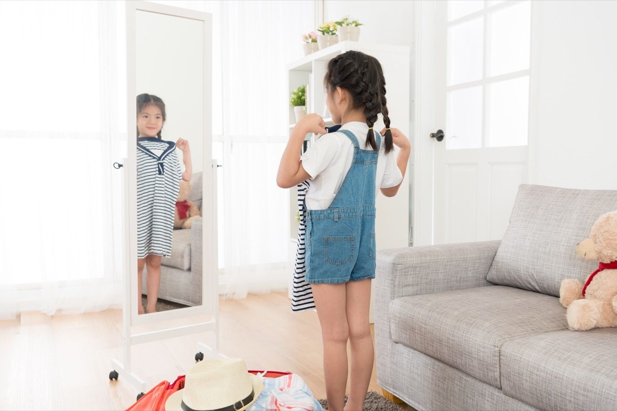 Pieni tyttö katselee peiliin vaatetusvaihtoehtoja