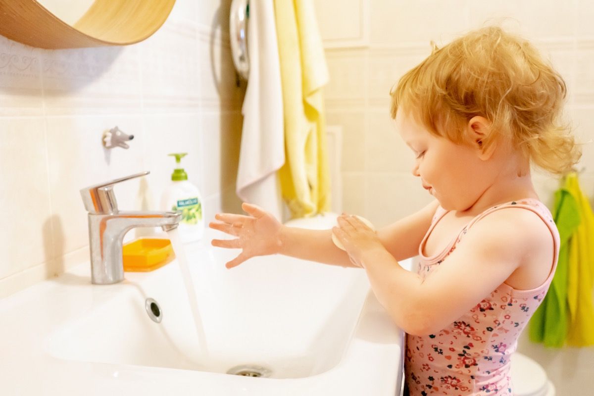 Toddler pige vasker hænderne i vasken i badeværelset