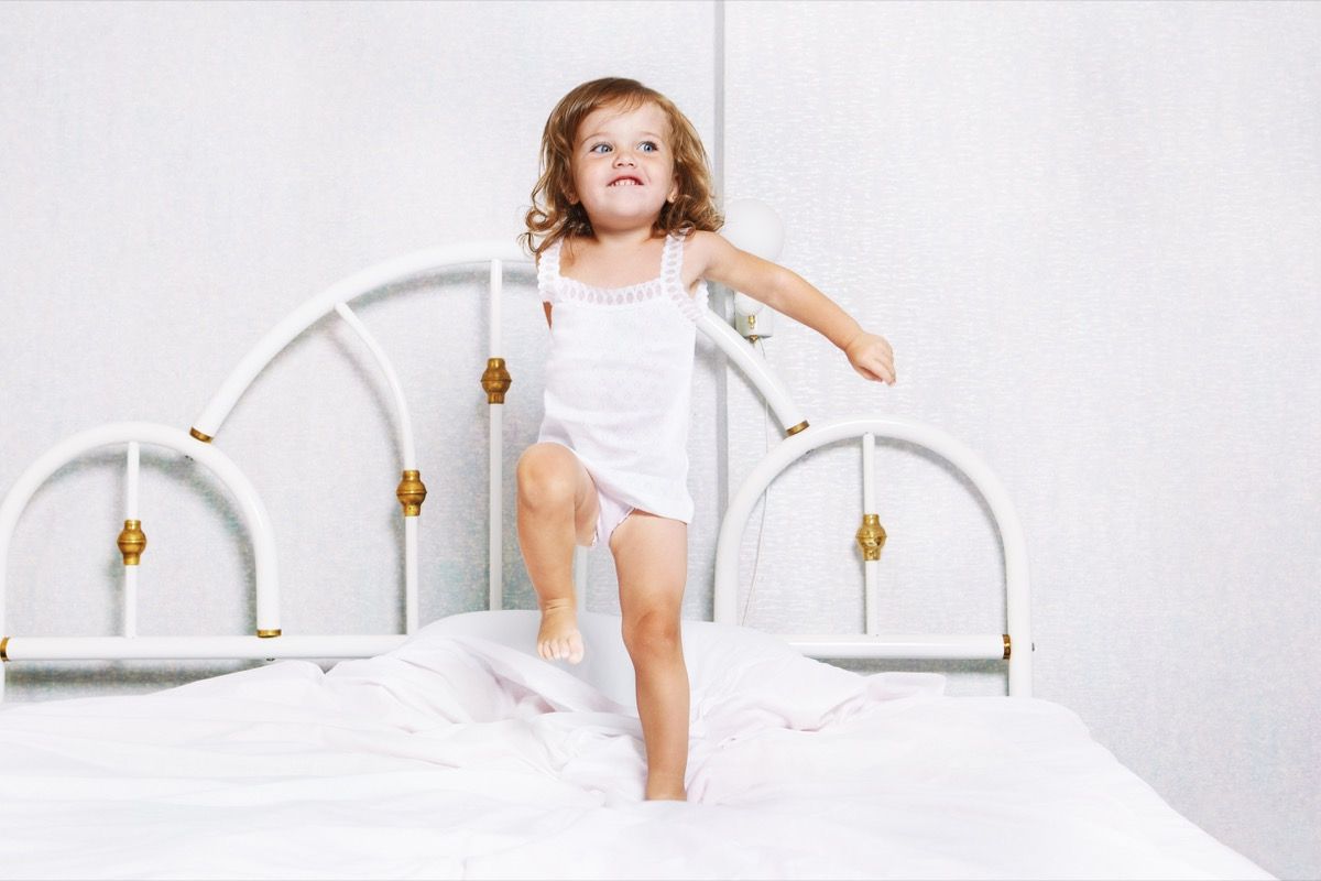 Κορίτσι μικρών παιδιών που πηδά στο κρεβάτι