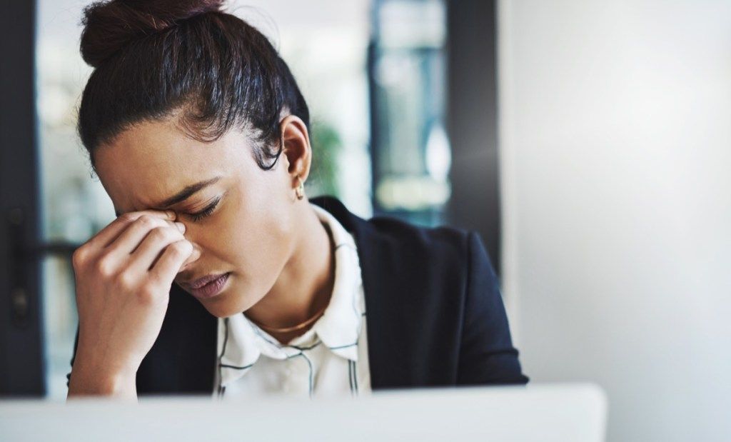 Posnetek mlade podjetnice, ki je videti v stresu, medtem ko je delala za pisalno mizo v sodobni pisarni