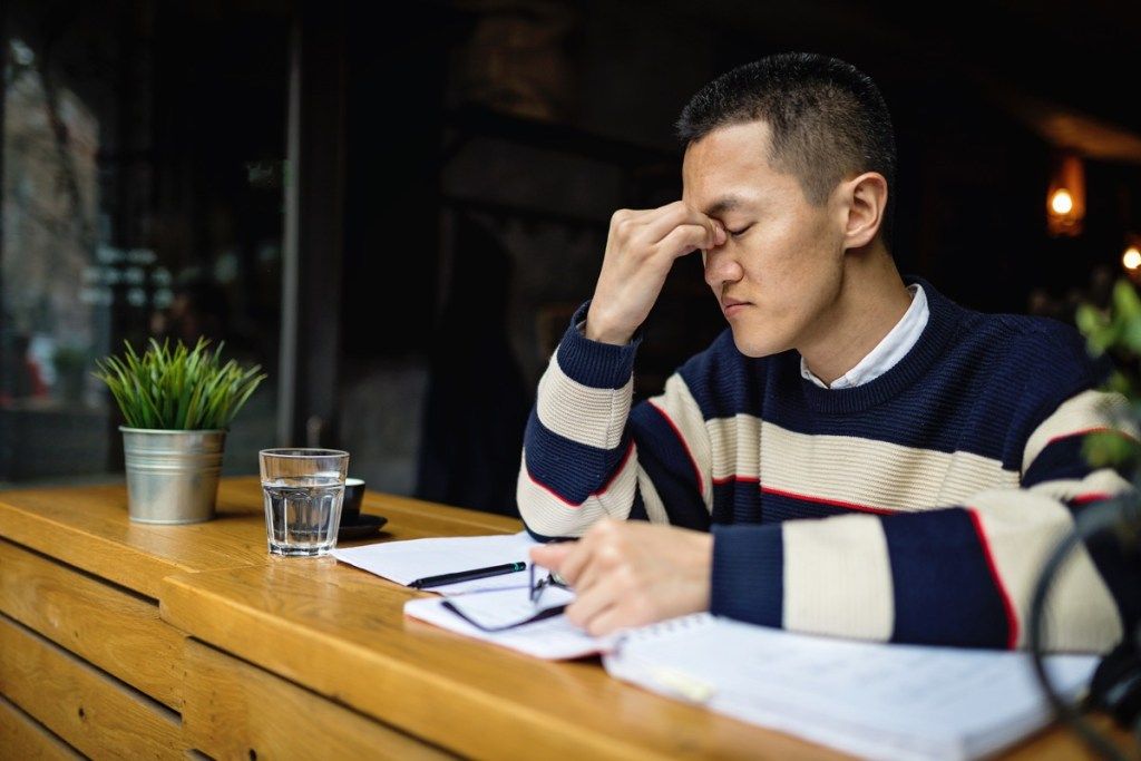 Успешен млад японски работник на свободна практика, организиращ времето си, докато седи в кафене