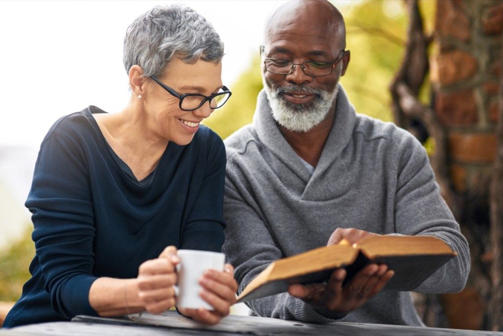 Apkarpytas meilaus vyresnio amžiaus pora, skaitantis savo Bibliją, sėdėdamas lauke