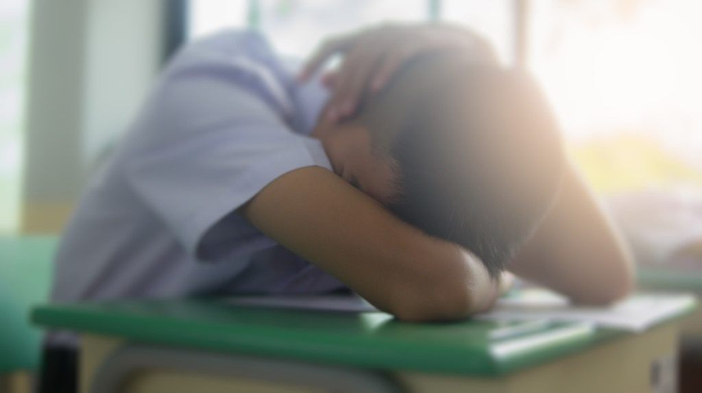 机で寝ている学生