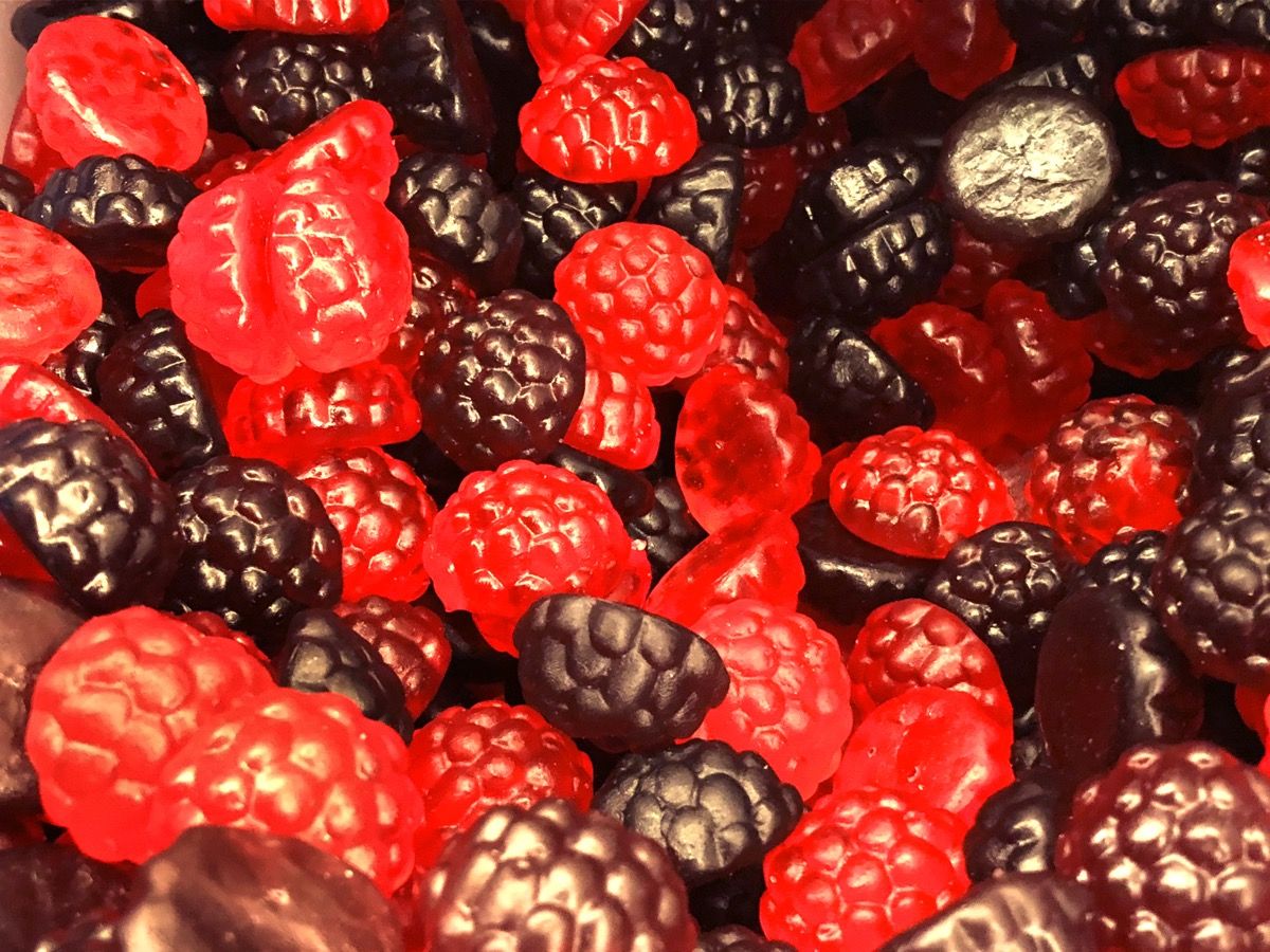 Fotografie sladkého obchodu pic a mix zobrazení fialového a červeného želé sladkého / gumovitého bobulovitého ovoce ve tvaru ostružin a malin.