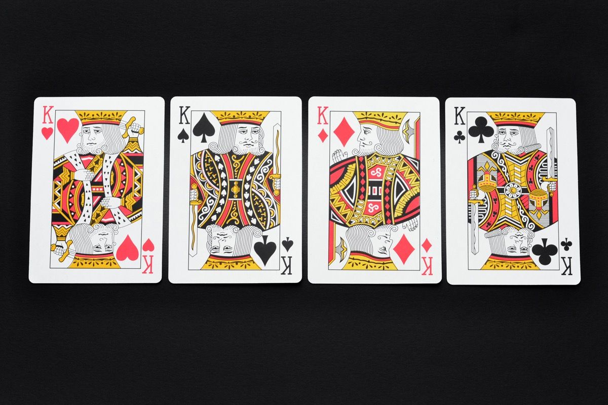 Zblízka čtyř králů v balíčku hracích karet na černém pozadí.
