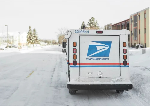   USPS, Jungtinių Valstijų pašto tarnyba, furgonas stovėjo priemiesčio gatvėje žiemą, kai daug sniego.
