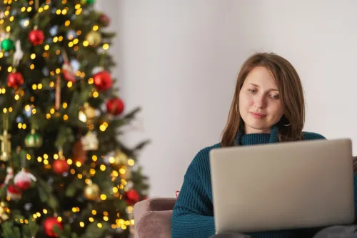   žena nakupování na notebooku s vánoční stromeček za ní