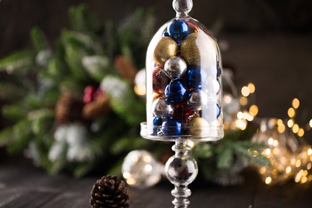 campana de cristal transparente llena de adornos navideños azules y dorados