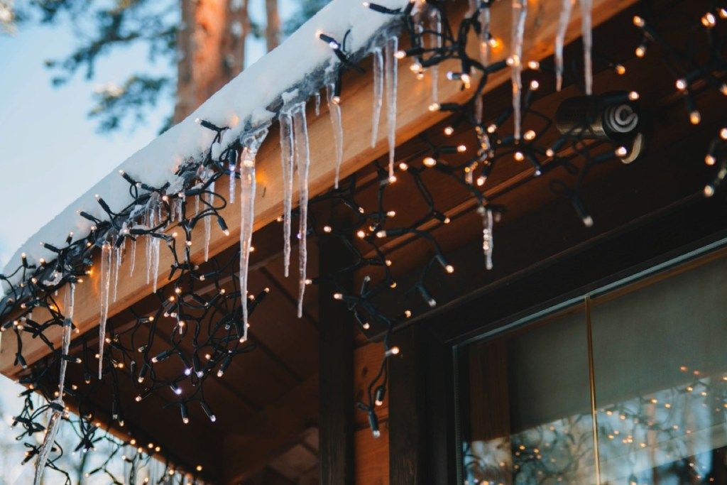 oświetlenie sopli i sople zwisające z krawędzi zaśnieżonego dachu