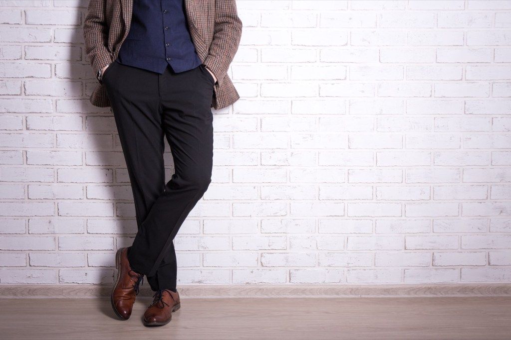 mies yllään ruudullinen bleiseri mustat housut ja ruskeat kengät