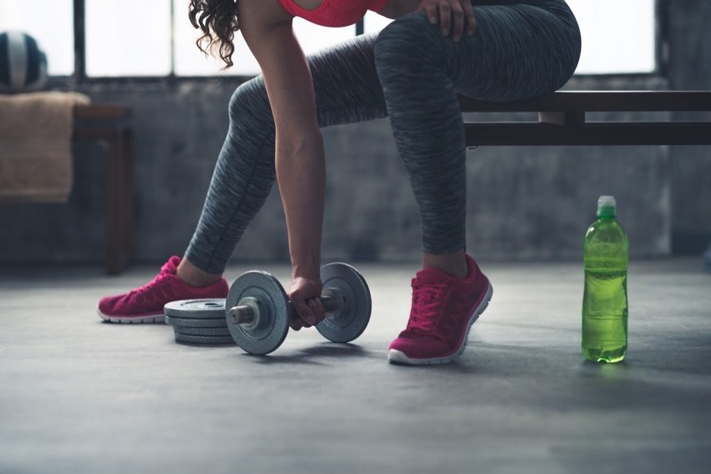 मांसपेशियों को जोड़ने के लिए डम्बल व्यायाम उठाने वाली महिला