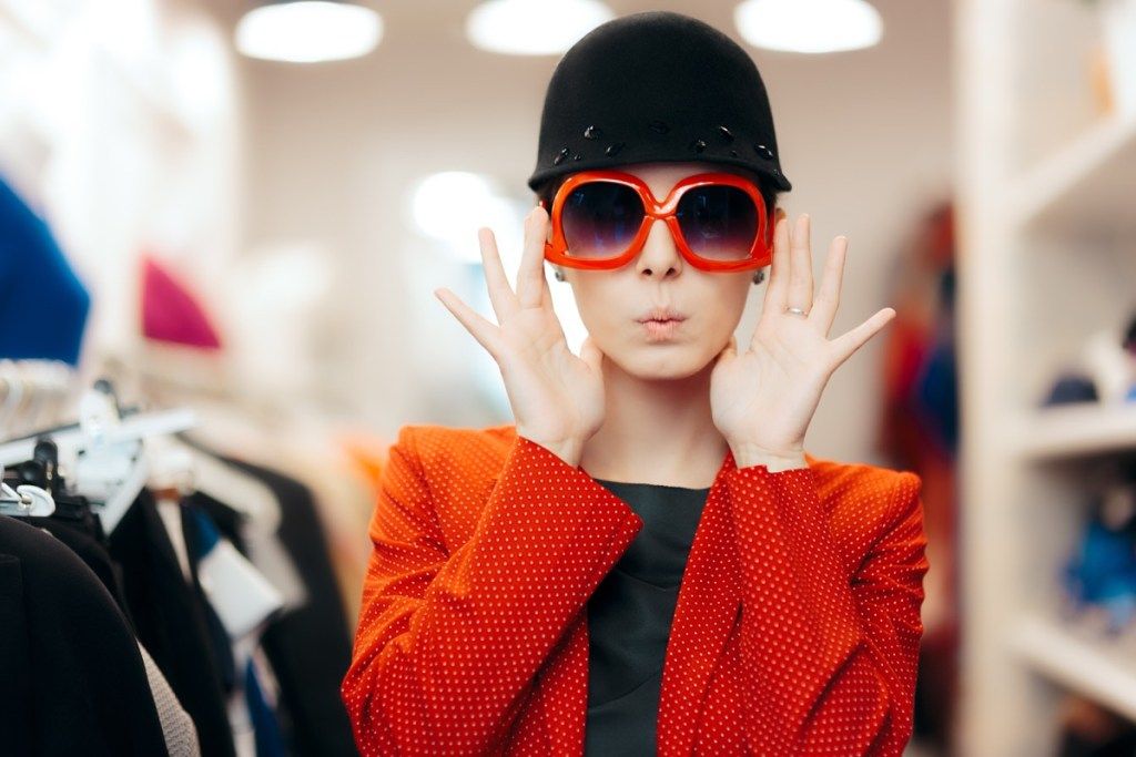 ผู้หญิงคนหนึ่งกำลังลองแว่นกันแดดสีแดงขนาดใหญ่ในร้านเพื่อสุขภาพที่ปรับแต่งได้มากกว่า 40 ชิ้น