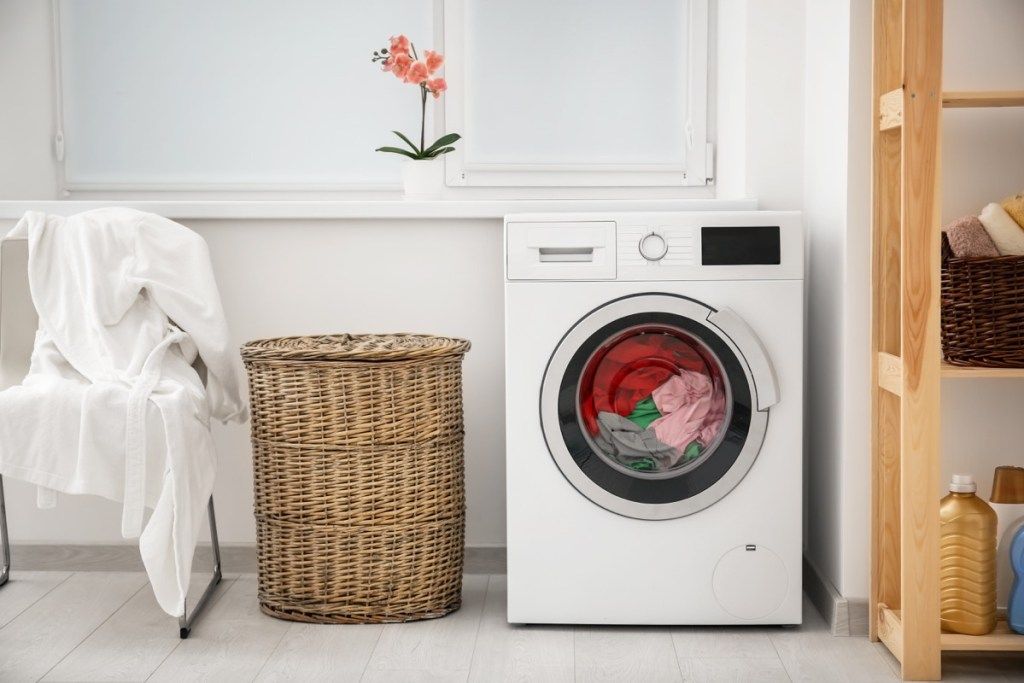 कपड़े धोने की मशीन और टोकरी में कपड़े धोने - घर के अंदर