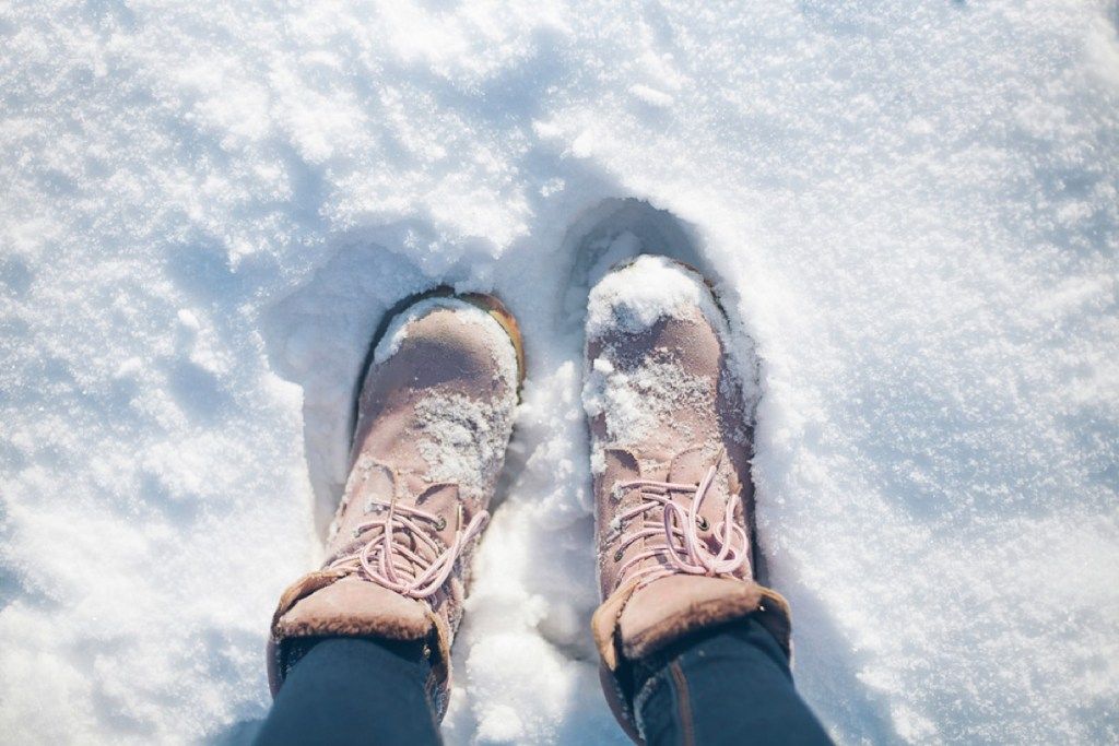 kvinne som går i snø i rosa støvler