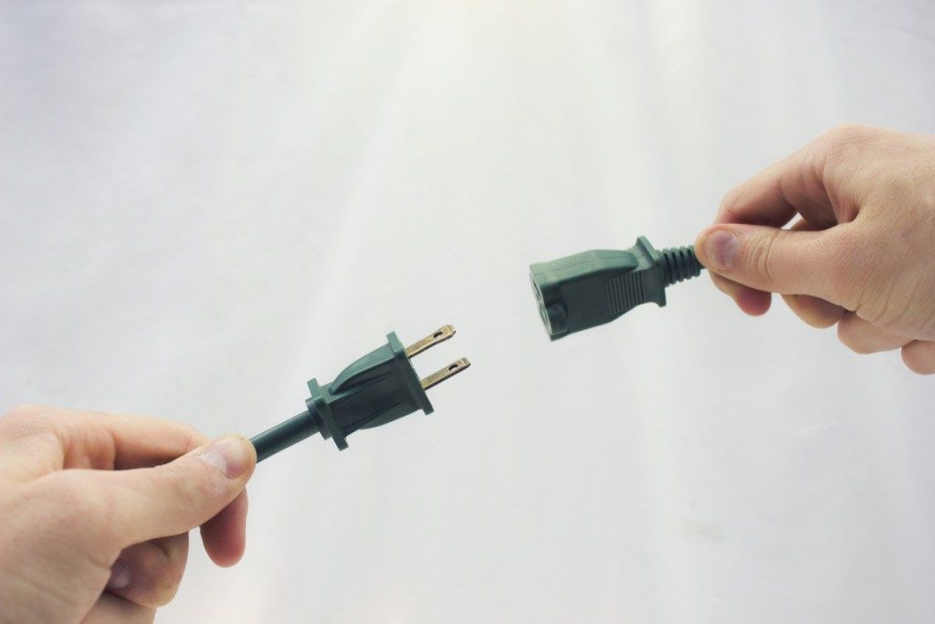 manos blancas conectando dos cables verdes entre sí