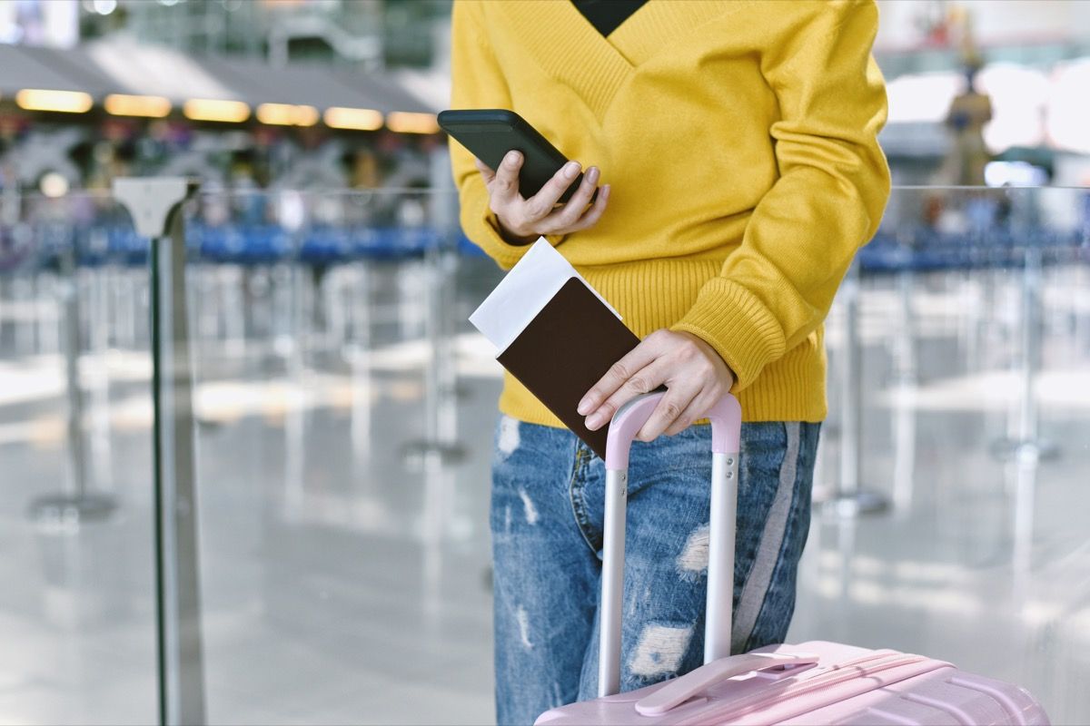 мъж, който държи самолетни билети и куфар на летището